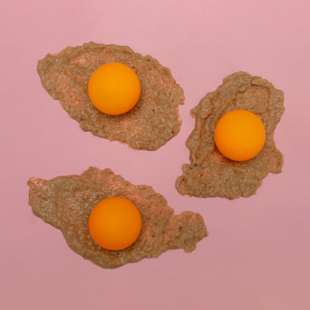 Egg made of creme and orange balls against pink background. Flat lay. Creative patternの写真素材