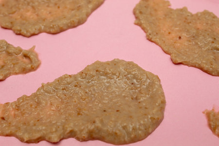 Texture of walnut and cinnamon cream on pink background
