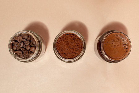 Roasted, ground and brewed coffee in jars on a beige backgroundの写真素材