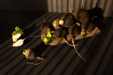 Black radishes on the table on black background. Still lifeの写真素材