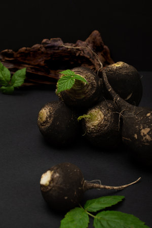 Black radishes on the table on black background. Still lifeの写真素材