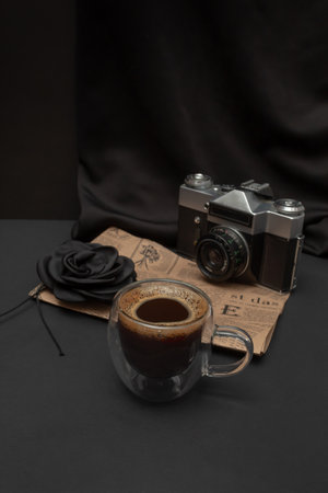 Black coffee in a lighted cup with additional elements and a black background.