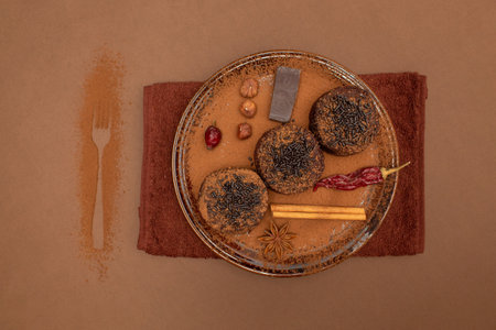 Brownies with cocoa powder and chocolate sprinkles and spices on brown plateの写真素材