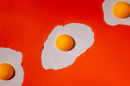 Eggs made of orange torn paper on a white background with ping pong balls. Abstract creative patternの写真素材