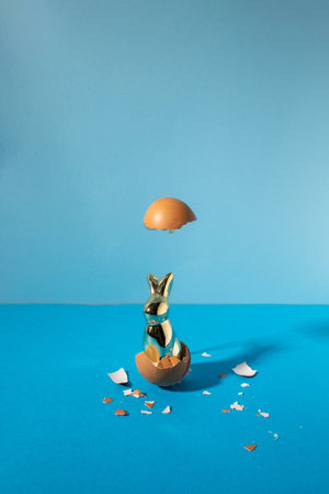 Eggshell with bunny rabbit. Creative copy space on pastel blue background. Minimal Easter holiday...