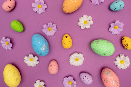 Creative layout made with colorful flowers and Easter eggs. Minimal nature purple background. Spring...
