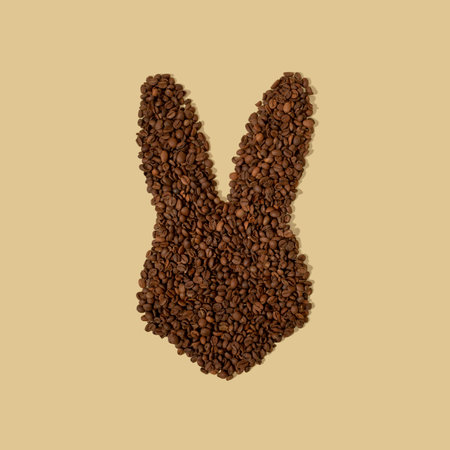Rabbit ears made of a coffee beans on a light beige background with copy space. Easter minimalism.の写真素材
