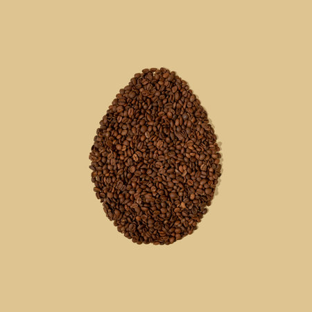 Easter egg made of a coffee beans on a light beige background with copy space. Easter minimalism.の写真素材