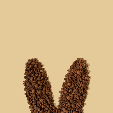 Rabbit ears made of a coffee beans on a light beige background with copy space. Easter minimalism.の写真素材