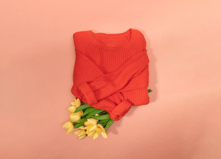 Orange jumper with bouquet of flowers. Women's stylish clothes. Fashionable look. Flat lay, top viewの写真素材