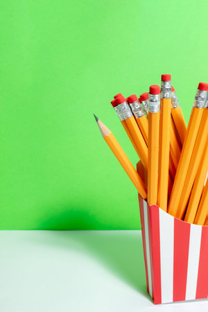 Graphite orange pencils in red-white box for french fries close on the green wall. Back to schoolの写真素材