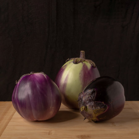 Eggplants on a wooden kitchen table with black background. Still lifeの写真素材