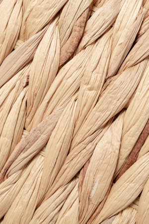 Close-up of natural woven straw texture. Rustic braided rattan surface in neutral beige tones....