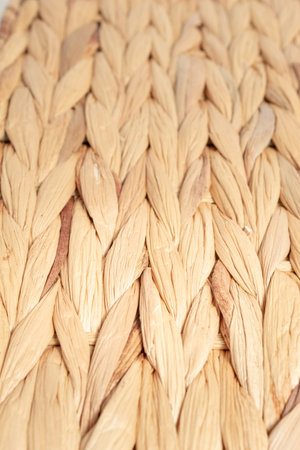 Close-up of natural woven straw texture. Rustic braided rattan surface in neutral beige tones....