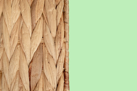 Close-up of natural woven straw texture with mint pastel copy space. Rustic braided rattan surface...