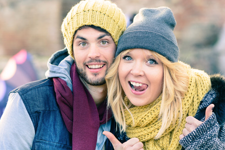 Happy hipster couple in love take a selfie photo during sunny day in autumn. Best friends with winter clothes sharing free time in the city and make shopping. Concept of lovers enjoying life moments.の写真素材