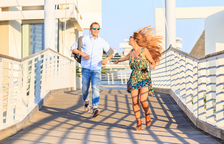 Happy hipster couple on holiday having fun and enjoy the time together. Dating young best friends in love enjoying life moments and running on bridge. Guys in city looking each other and flirtingの写真素材