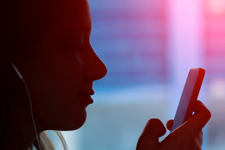 Silhouette of young girl with a phone sitting in the train and listening music - Face of a women...