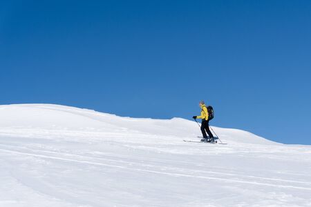 Panoramic view of healthy male person cross-country skiing in beautiful nordic winter landscape in Austria with blue sky background. Young man doing active outdoor sport exercise in winter wonderland.の写真素材