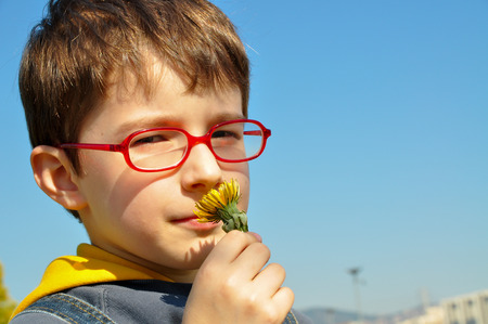 A boy smelling flowers in a fieldの写真素材