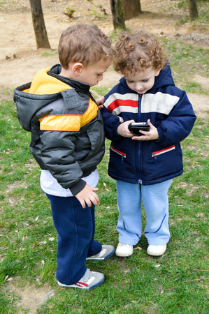 Two cute children playing with mobile phoneの写真素材