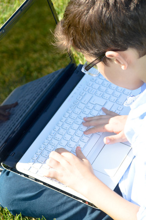 Child using a laptop on the grassの写真素材