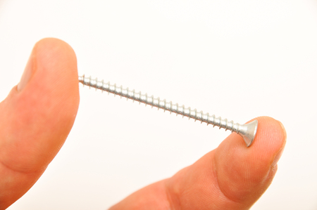Isolated chrome metal screw and fingers on white backgroundの写真素材