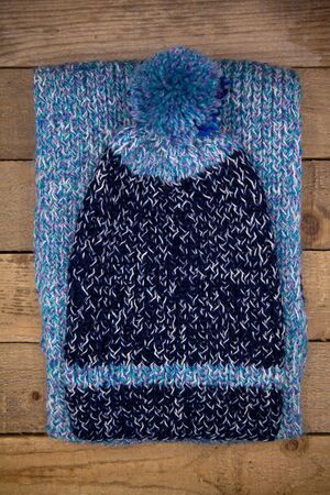 Handmade wool knitted winter blue hat and scarf isolated on old wood background