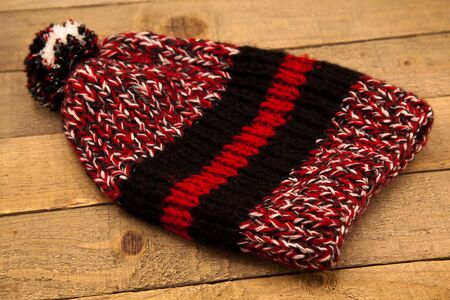 Handmade wool knitted winter hat and scarf isolated on old wood background