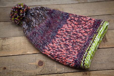 Handmade wool knitted winter hat and scarf isolated on old wood background