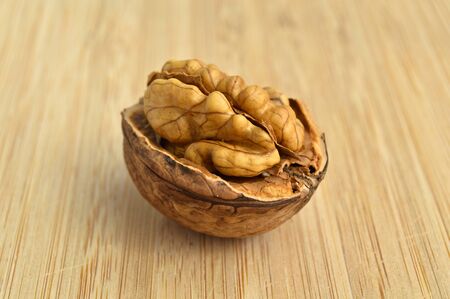 Healthy and nutritious beige brown walnut grains, bamboo on cutting board