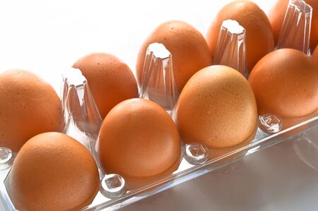 Fresh organic brown eggs in a plastic box package, isolated on white background