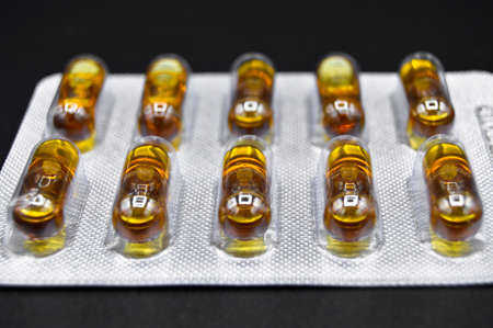 Yellow capsule pills isolated on black background, medical capsule pills