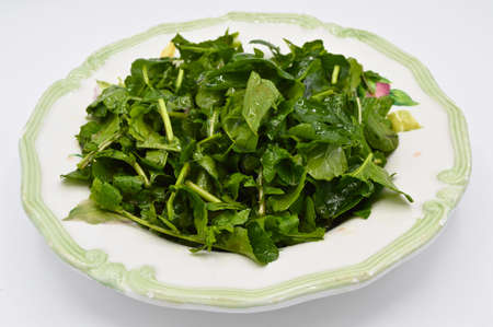 Fresh raw green healthy arugula salad in plate, isolated on white backgroundの写真素材