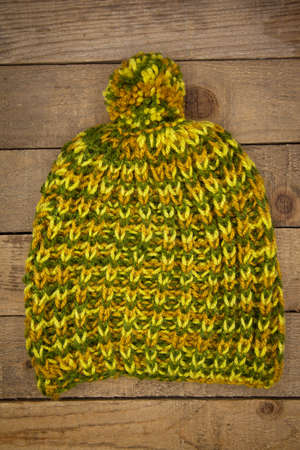 Handmade wool knitted winter hat and scarf isolated on old wood background