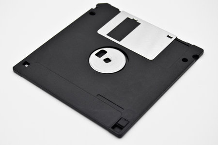 Old computer and data storage technology, black plastic magnetic floppy disk 3Â½ inches, isolated on white backgroundの写真素材