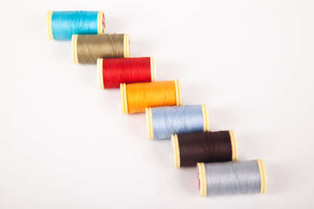 Spools and bobbins of thread for sewing in different colors, isolated on white background