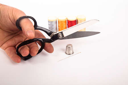 Sewing supplies concept, hand tailor scissors colorful threads needle and thimble, isolated on white...