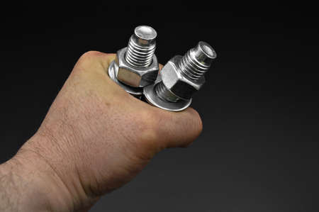 Galvanized steel metal dowel with metric bolt nut and hand, isolated on black background