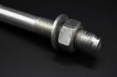 Galvanized steel metal dowel with metric bolt and nut, isolated on black background
