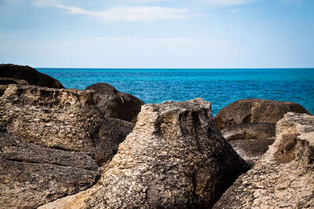 Interesting rock formations at the calm seaside, gray rocks by the ocean