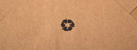 Brown and beige colored cardboard detail, black recycle sign on paper