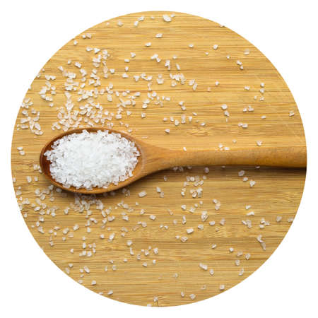 Table rock salt used in cooking in wooden spoon on bamboo cutting boardの写真素材