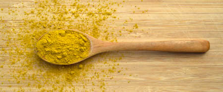 Aromatic fragrant organic curry spice, in wooden spoon on cutting board