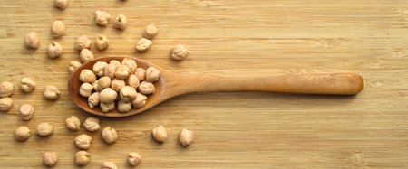 Very nutritious and heap of fresh dry chickpeas, wooden spoon inside and on wooden backgroundの写真素材