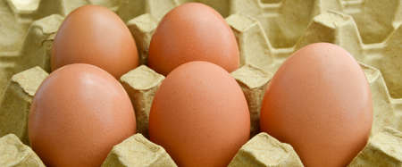 Fresh organic brown eggs in a carton box package, protected paper yellow egg box
