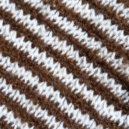 Pattern fabric made of wool. Handmade knitted fabric brown white wool background texture