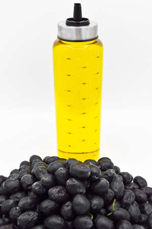 Fresh yummy black turkish olives and golden olive oil bottle, isolated on white backgroundの写真素材