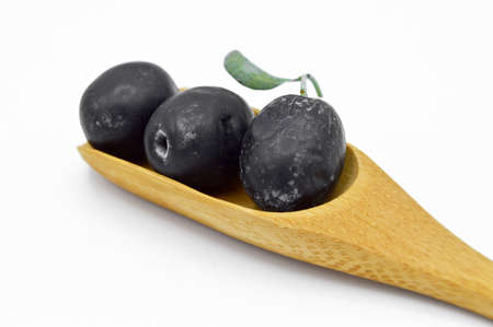 Fresh delicious black color turkish olives in bamboo spoon isolated on white backgroundの写真素材