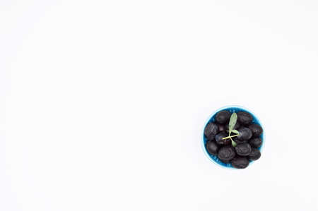 Fresh delicious black color turkish olives in blue plate isolated on white backgroundの写真素材